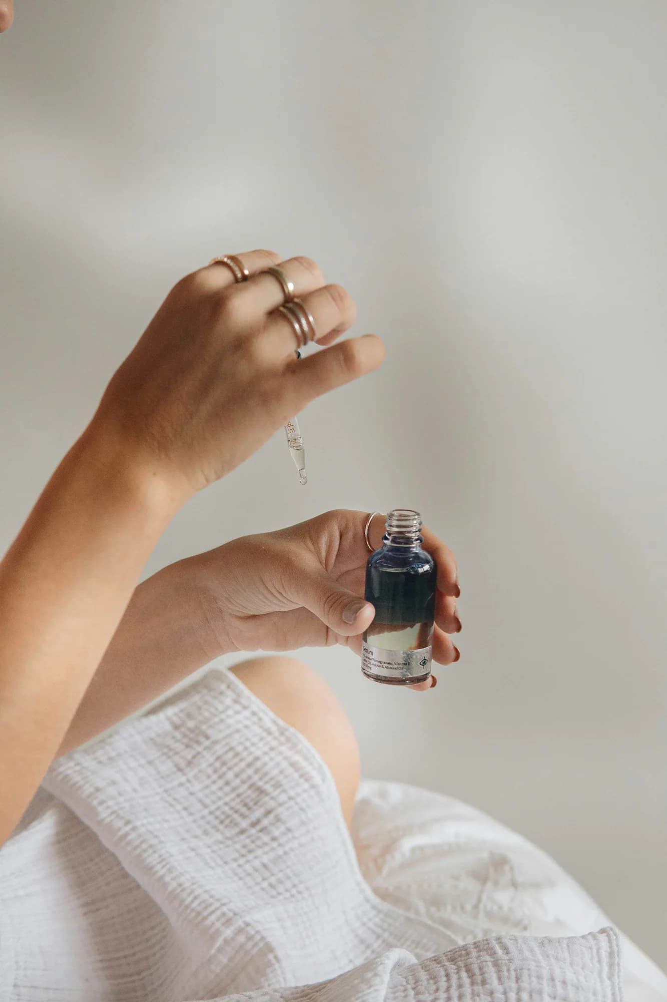 Hand holding a small dark glass serum bottle with a dropper