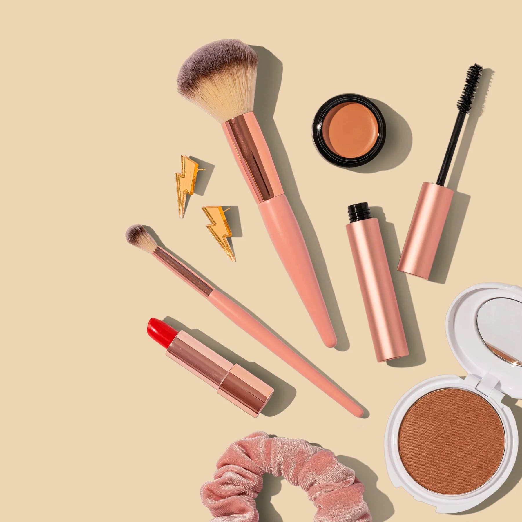 Makeup brushes and cosmetics on a beige background