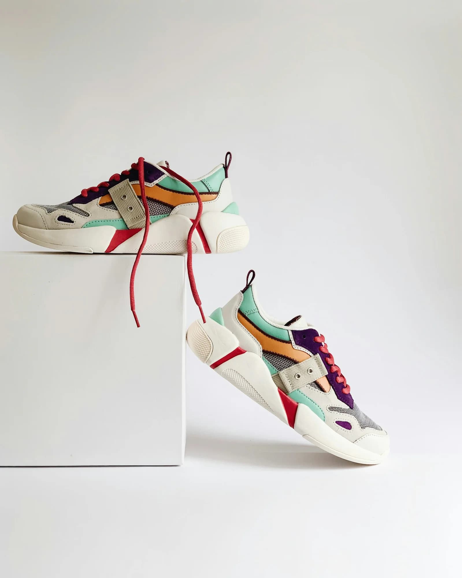 Multi-coloured chunky retro sneakers on white plinths