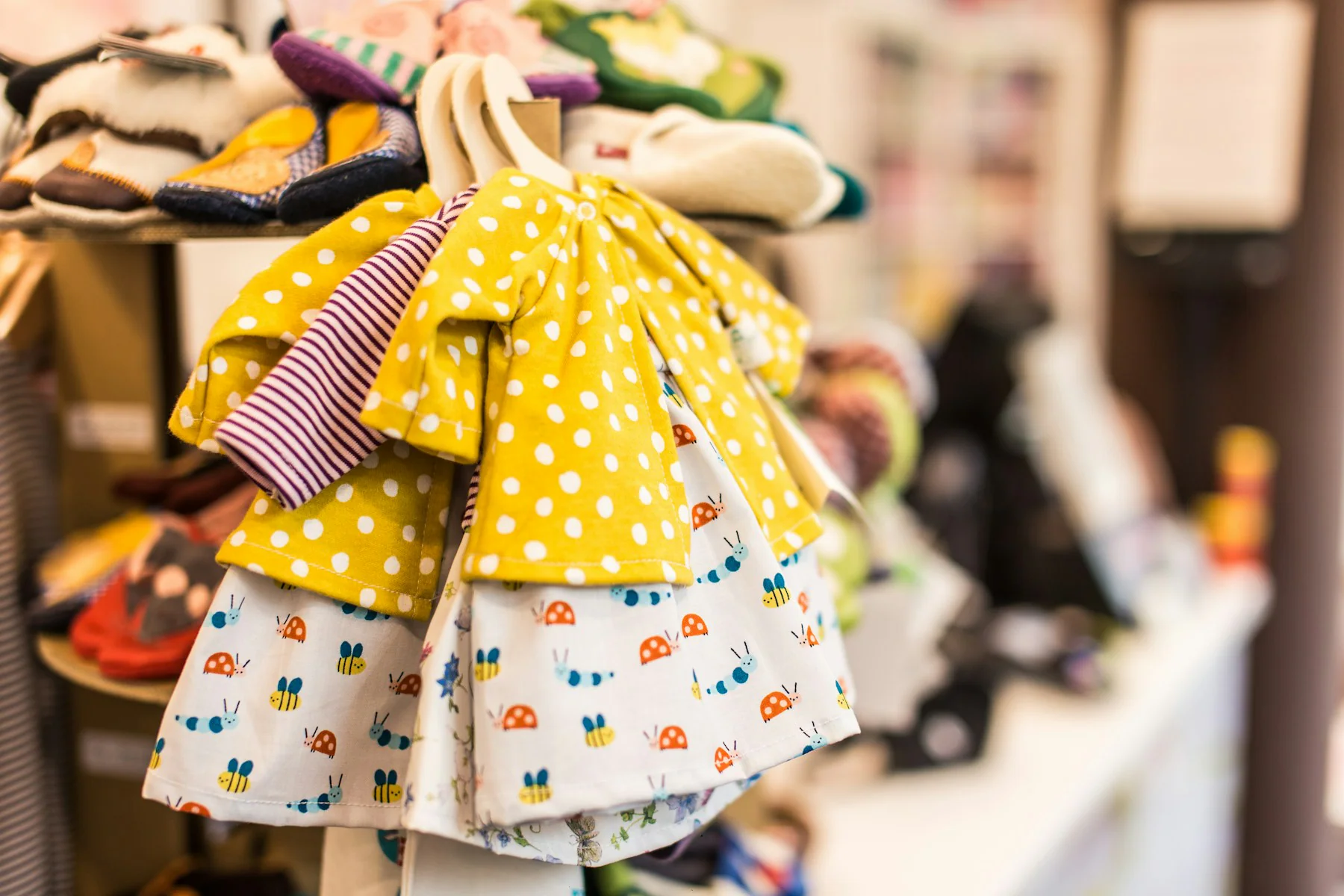 Two children's summer dresses in yellow prints on hangers