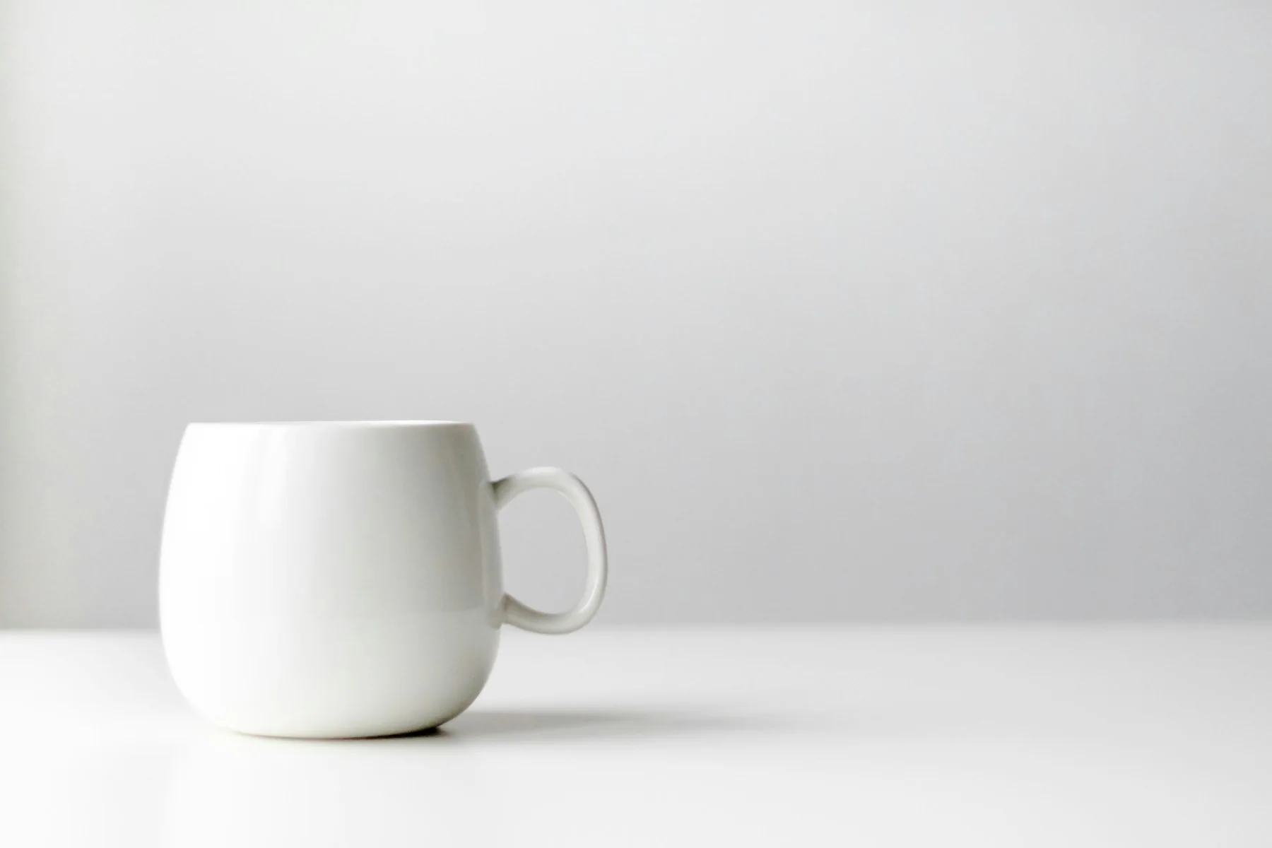 Plain white porcelain mug on a white surface
