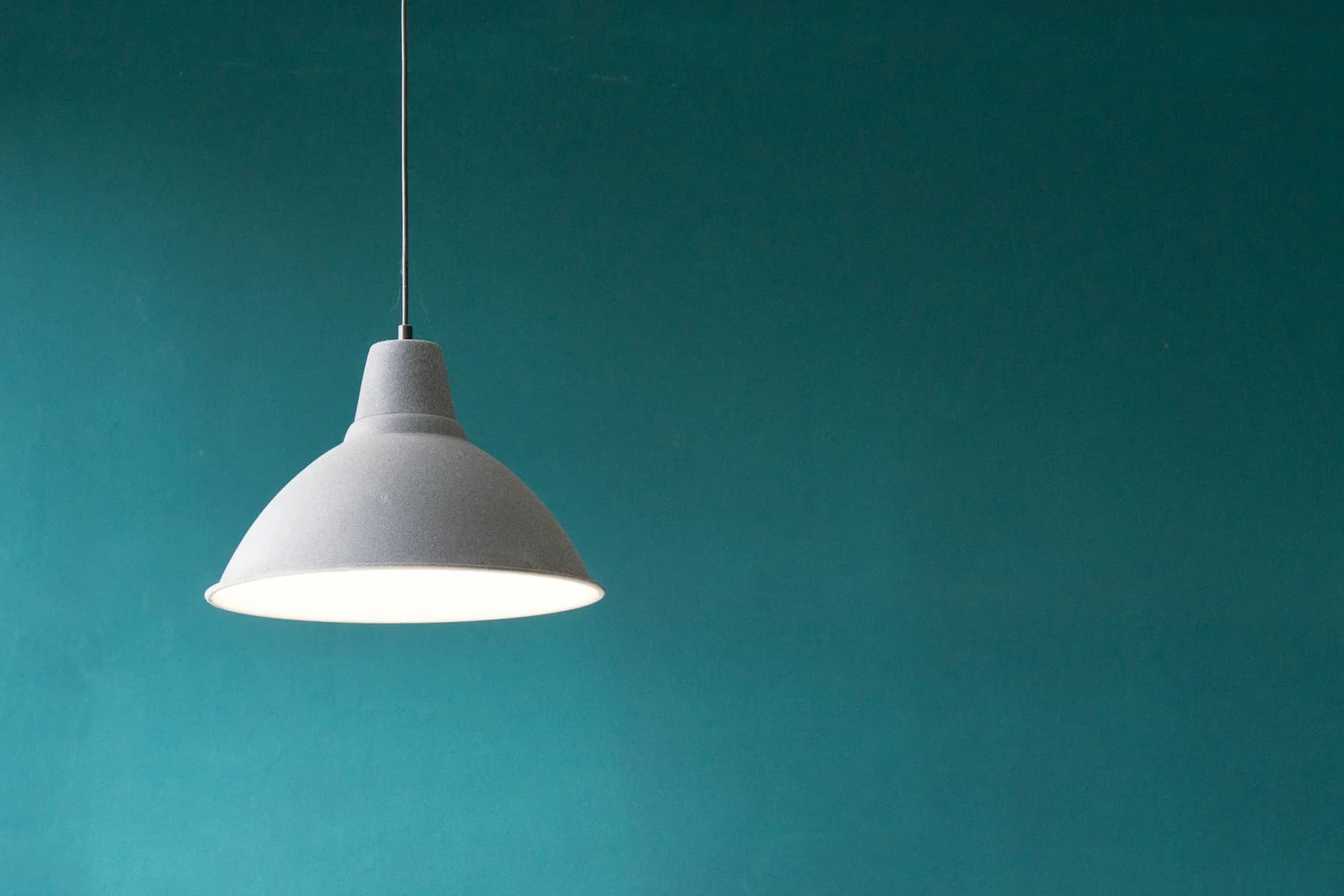 White dome pendant light against a teal wall