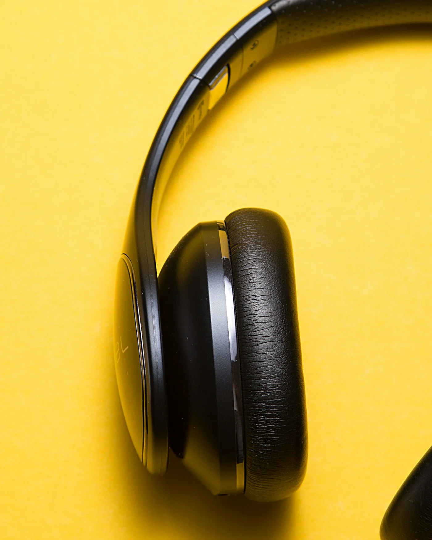 Black wireless headphones on a yellow background — detail