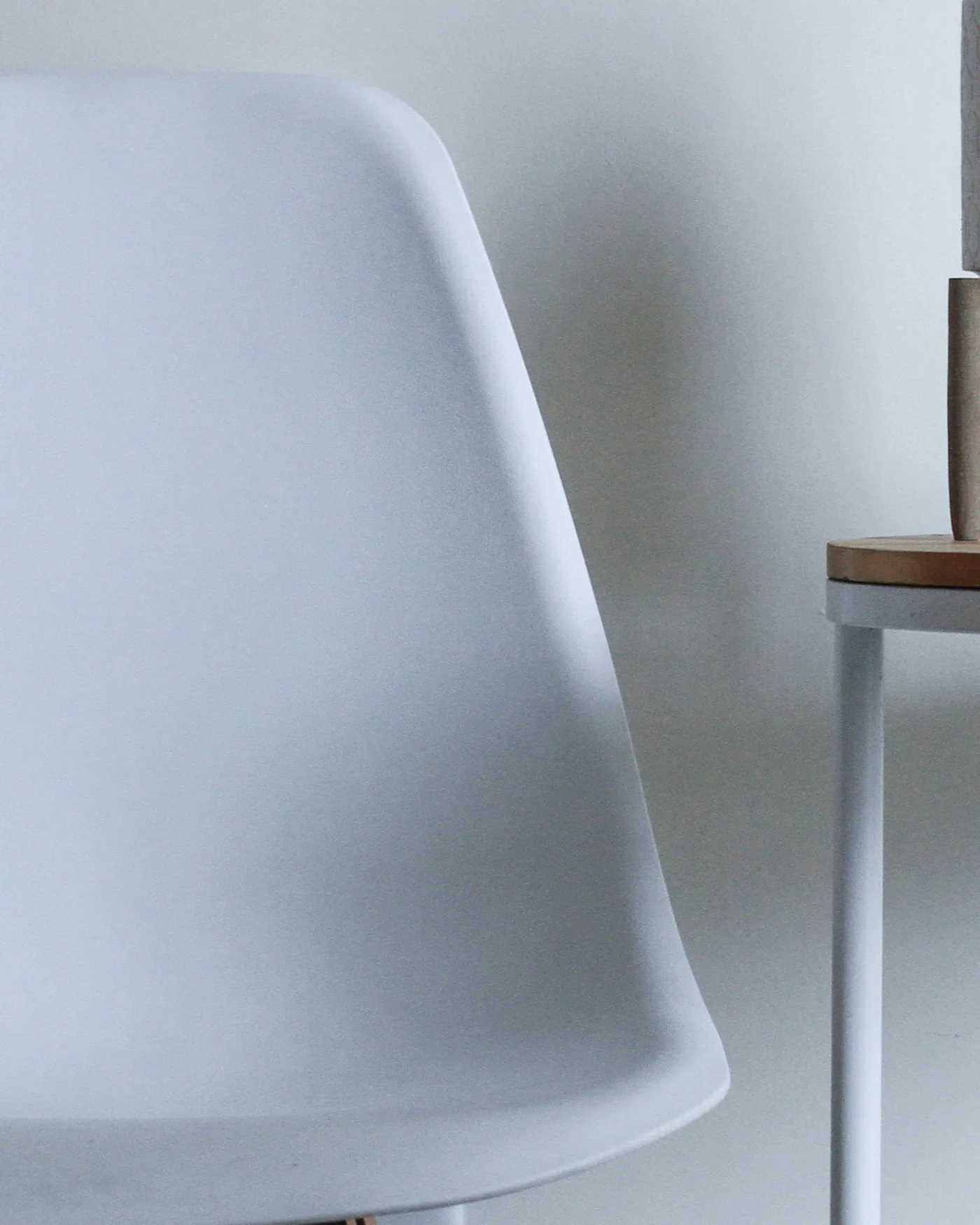 White moulded shell chair beside a plant — detail