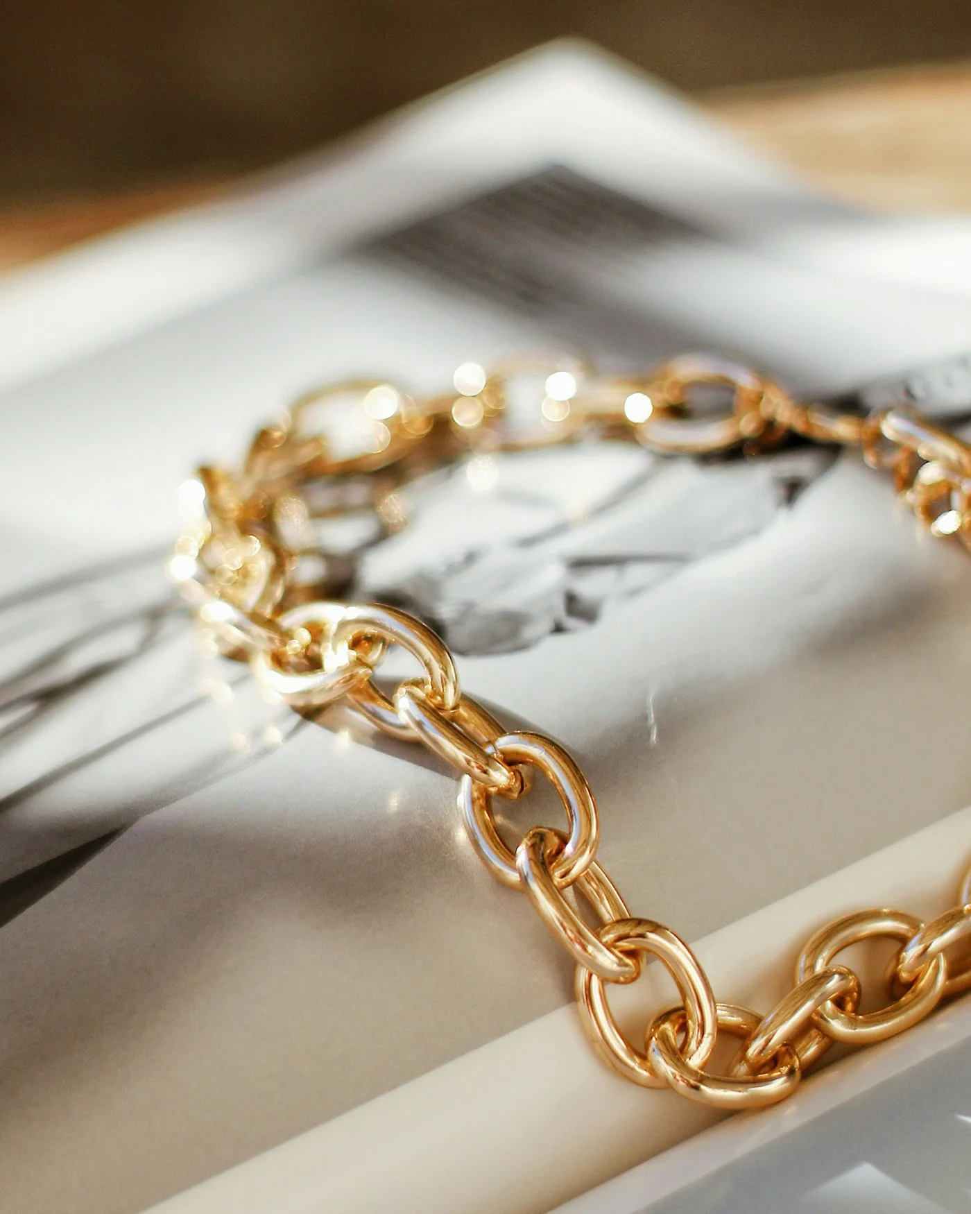 Gold curb chain bracelet on a book page — detail