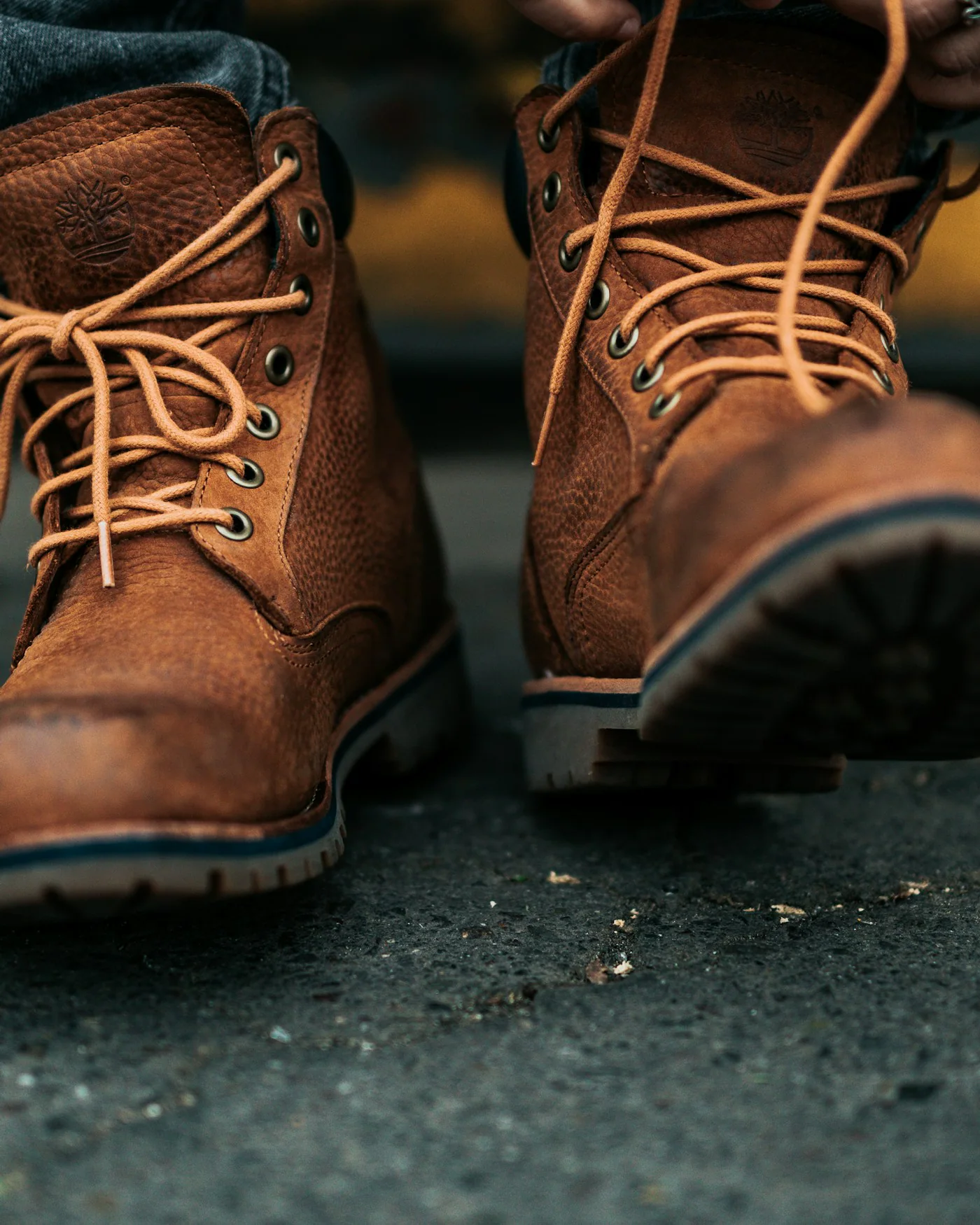 Person lacing brown leather work boots — detail
