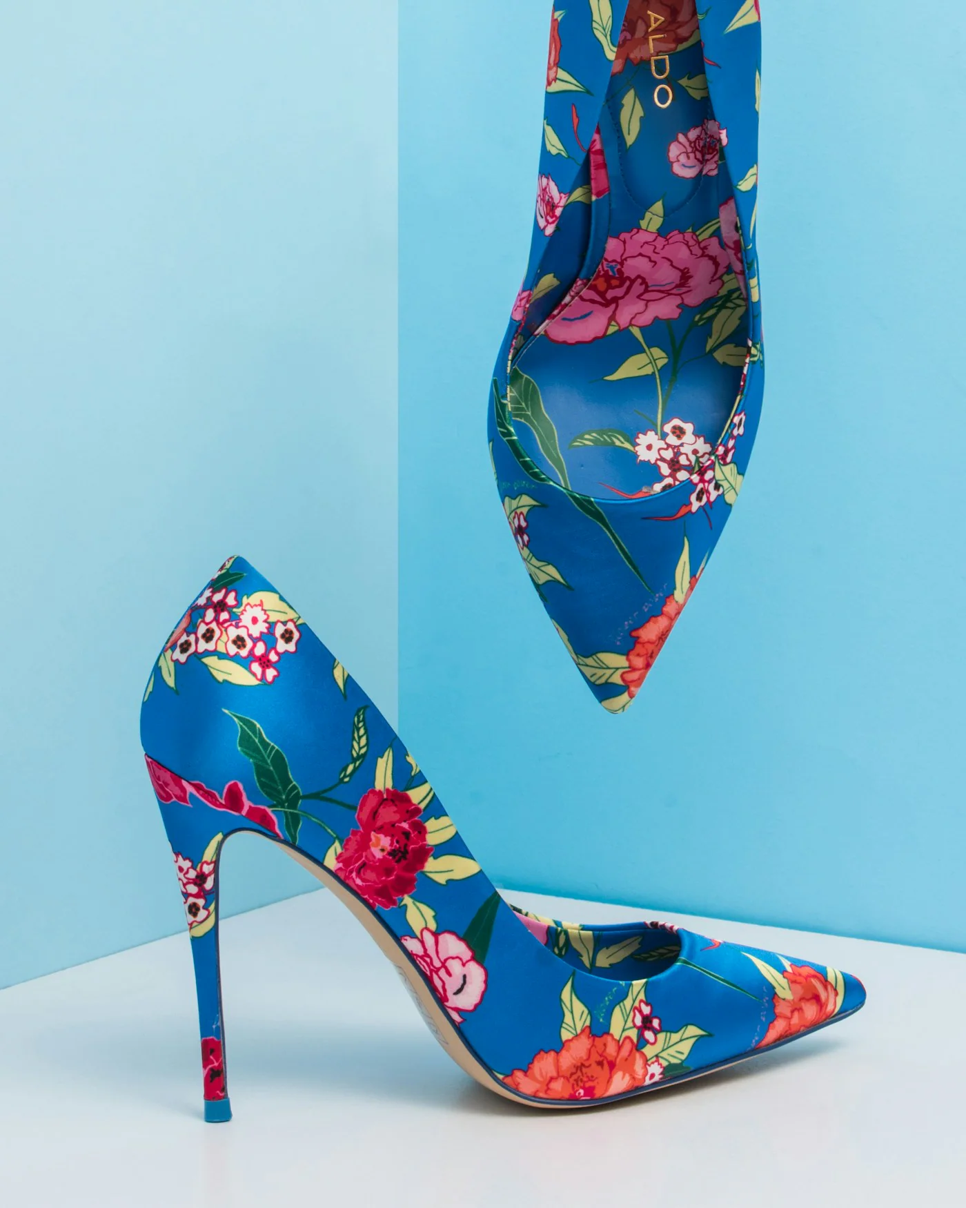 Pair of floral print stiletto heels against a blue background — detail