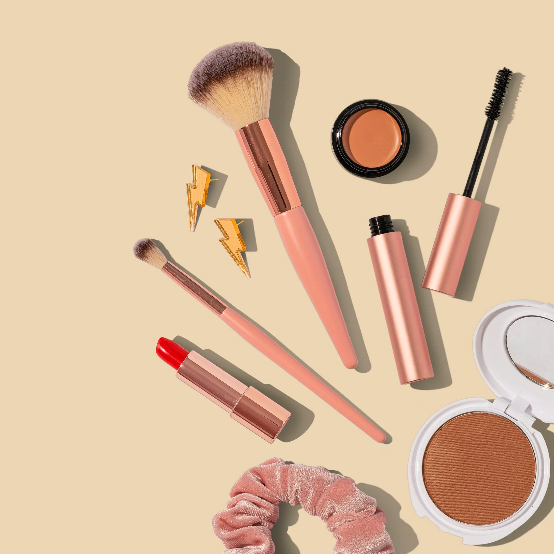 Makeup brushes and cosmetics on a beige background