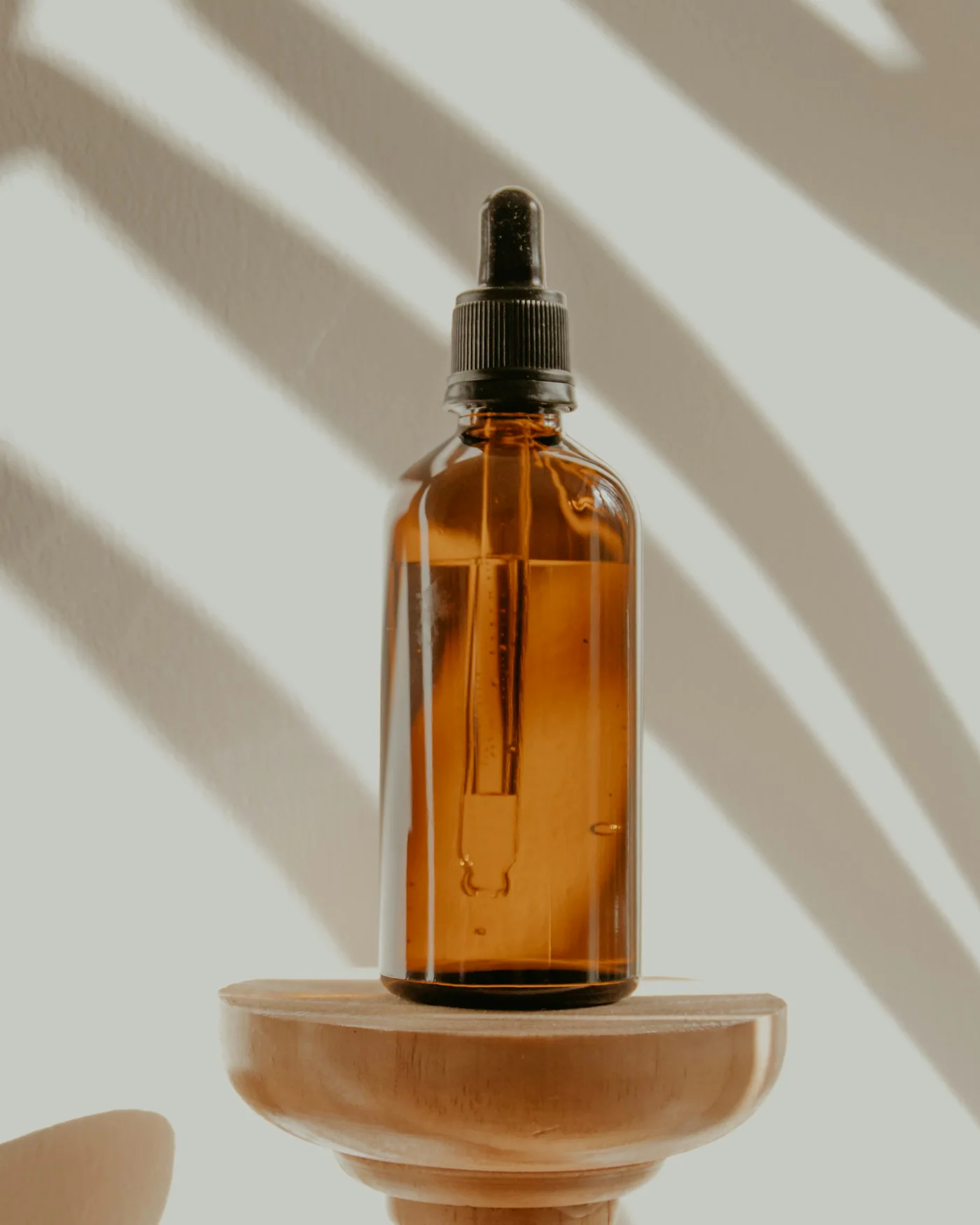 Amber serum bottle with dropper on a wooden stand — detail