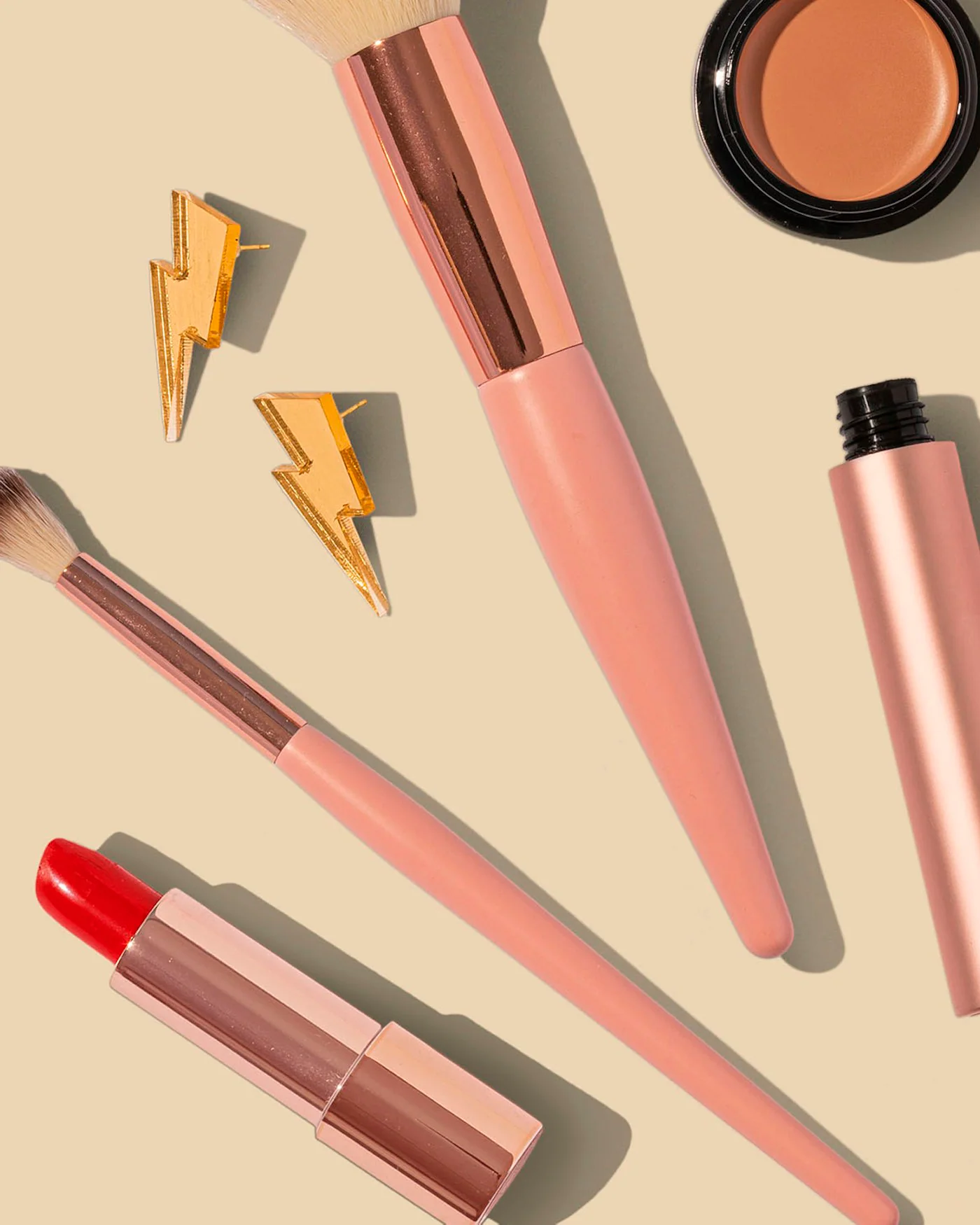 Makeup brushes and cosmetics on a beige background — detail
