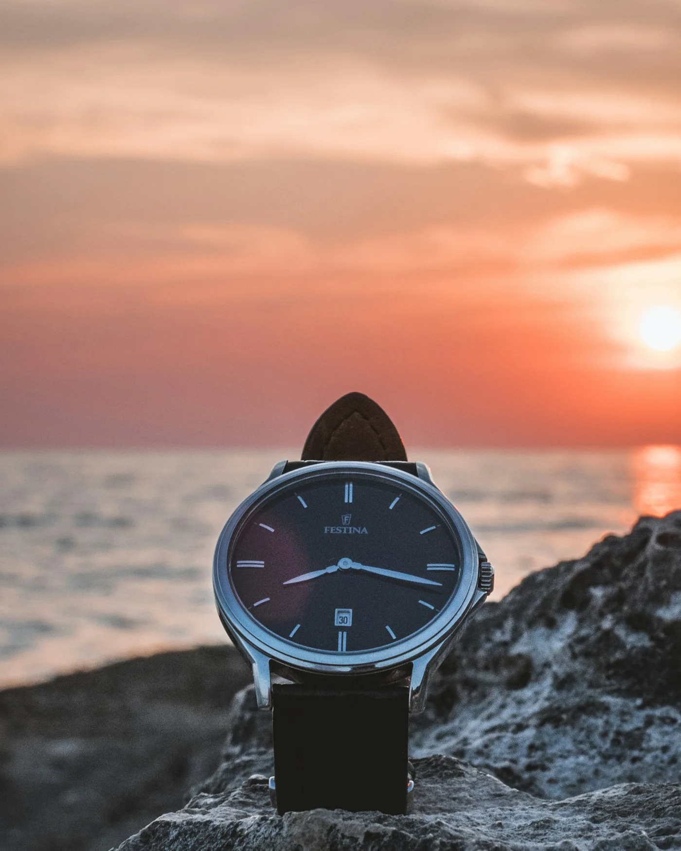 Field watch with a navy dial resting on a rock at sunset — detail