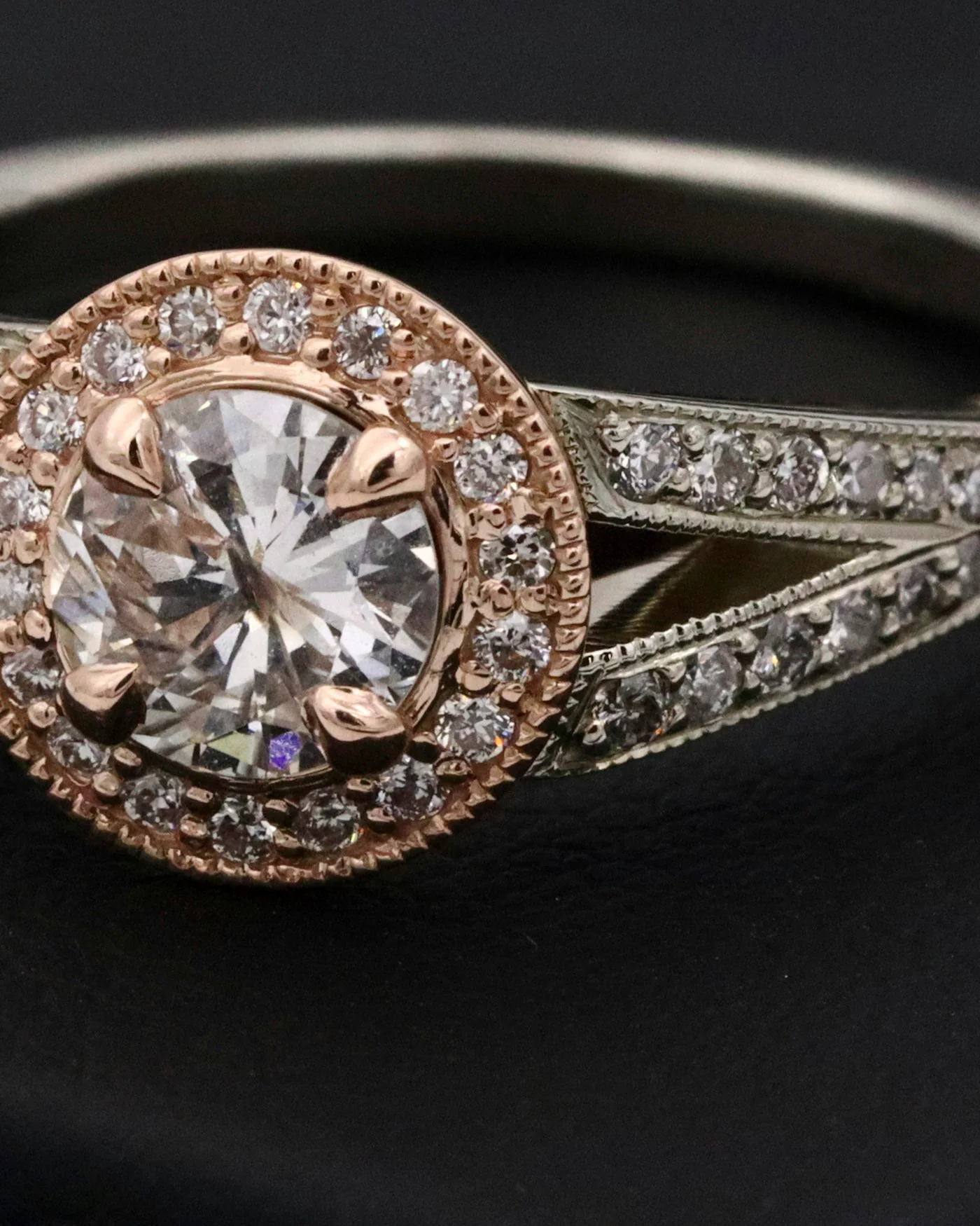 Diamond halo ring on a dark surface — detail