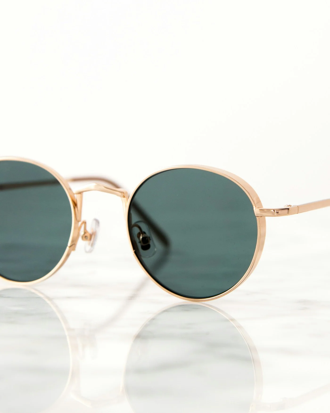 Round gold wire sunglasses with green lenses — detail