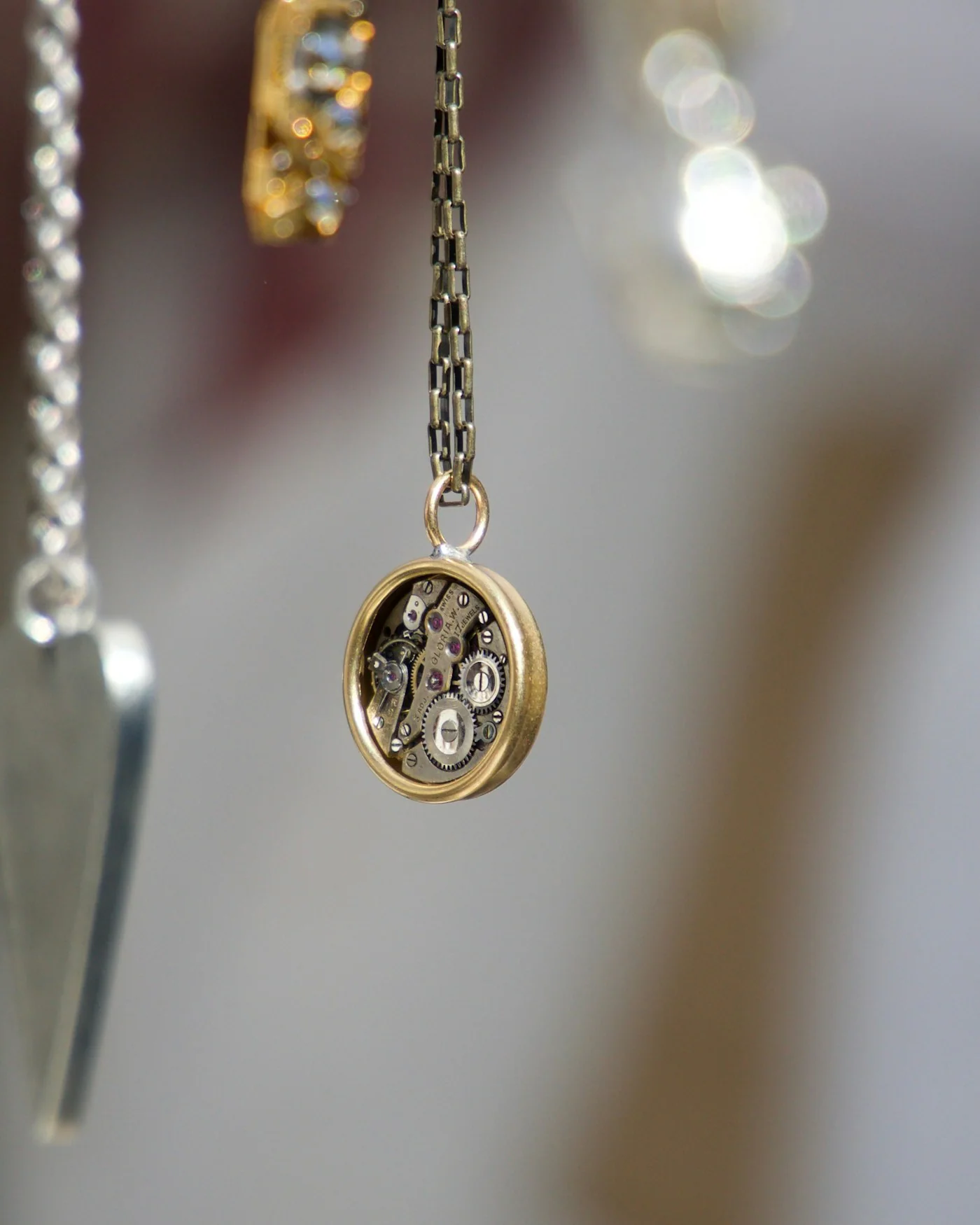 Three delicate gold charm necklaces hanging — detail