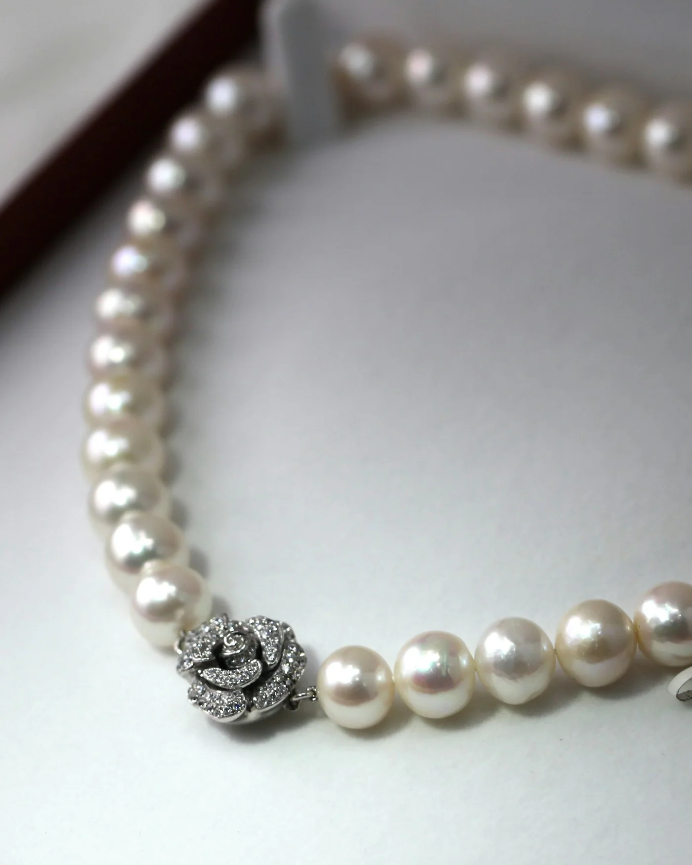 Pearl necklace in an open burgundy jewellery box — detail