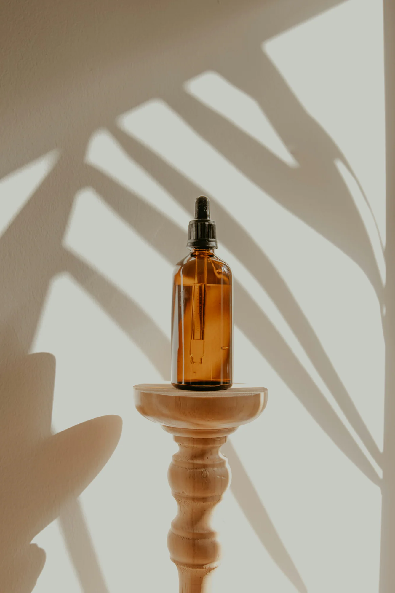 Amber serum bottle with dropper on a wooden stand