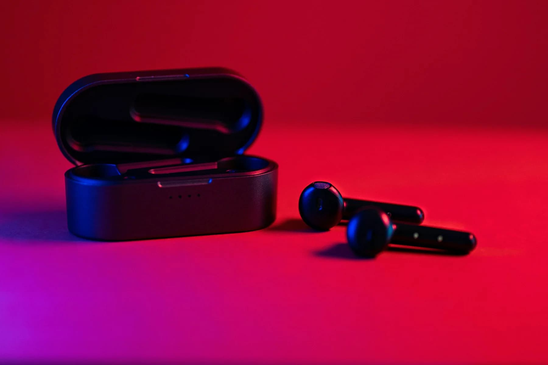 Black wireless earbuds and case on a red background